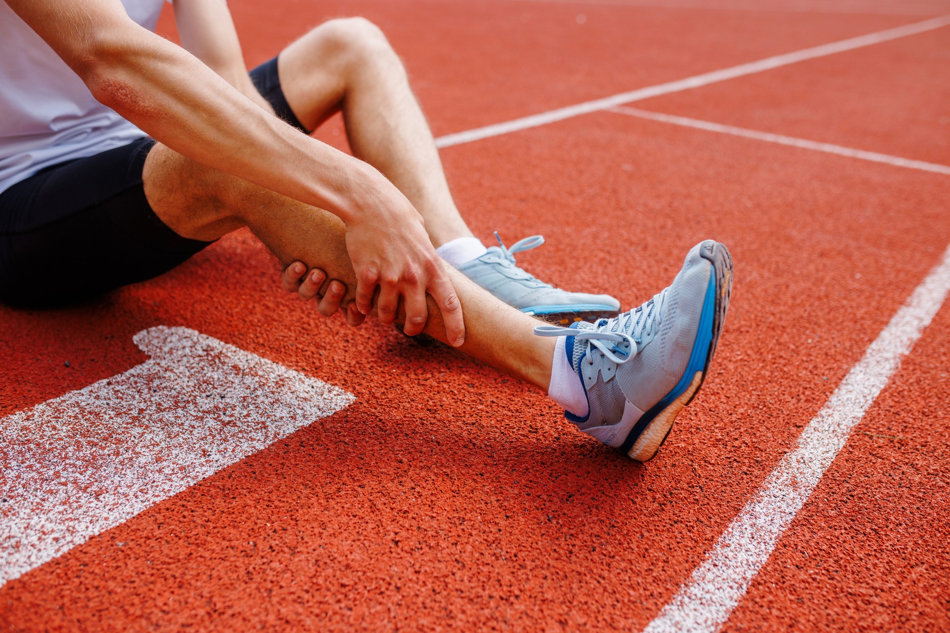 Athlete holding his leg injured after running at track and field stadium after jogging