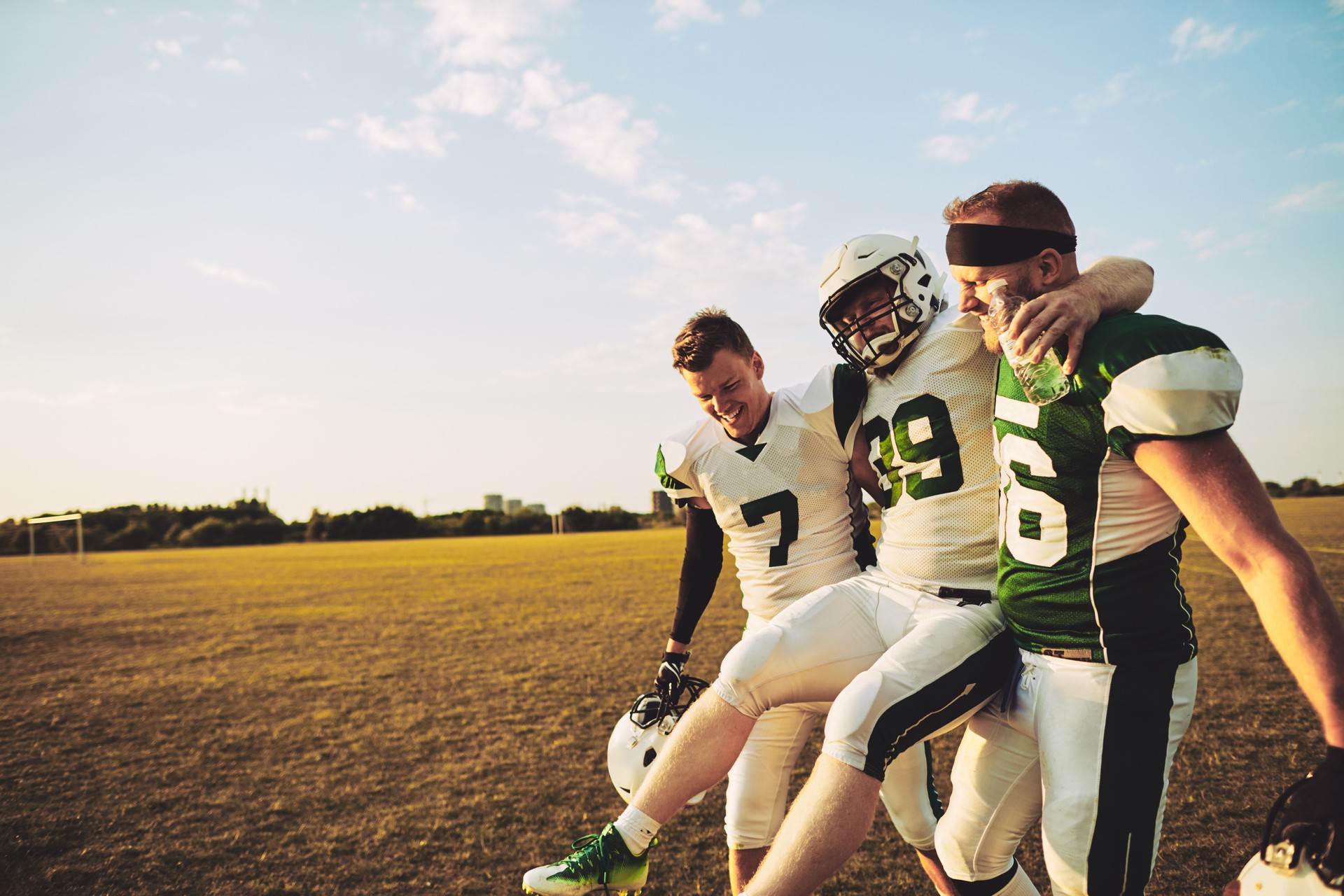 American football players carrying an injured teammate off the field